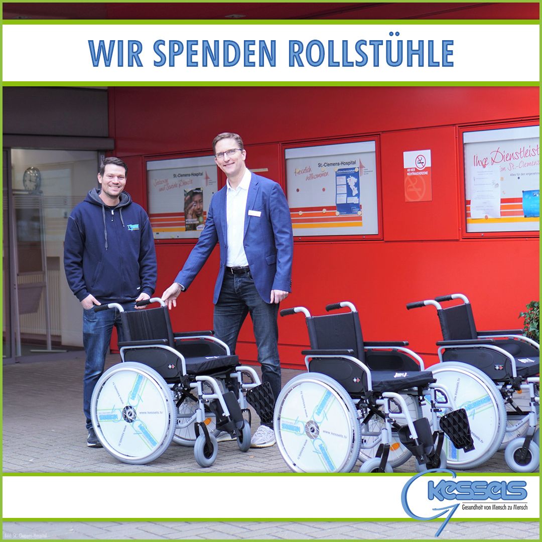 Zwei Männer stehen neben drei Rollstühlen vor einem roten Gebäude und werben mit einem Schild darüber für Rollstuhlspenden.