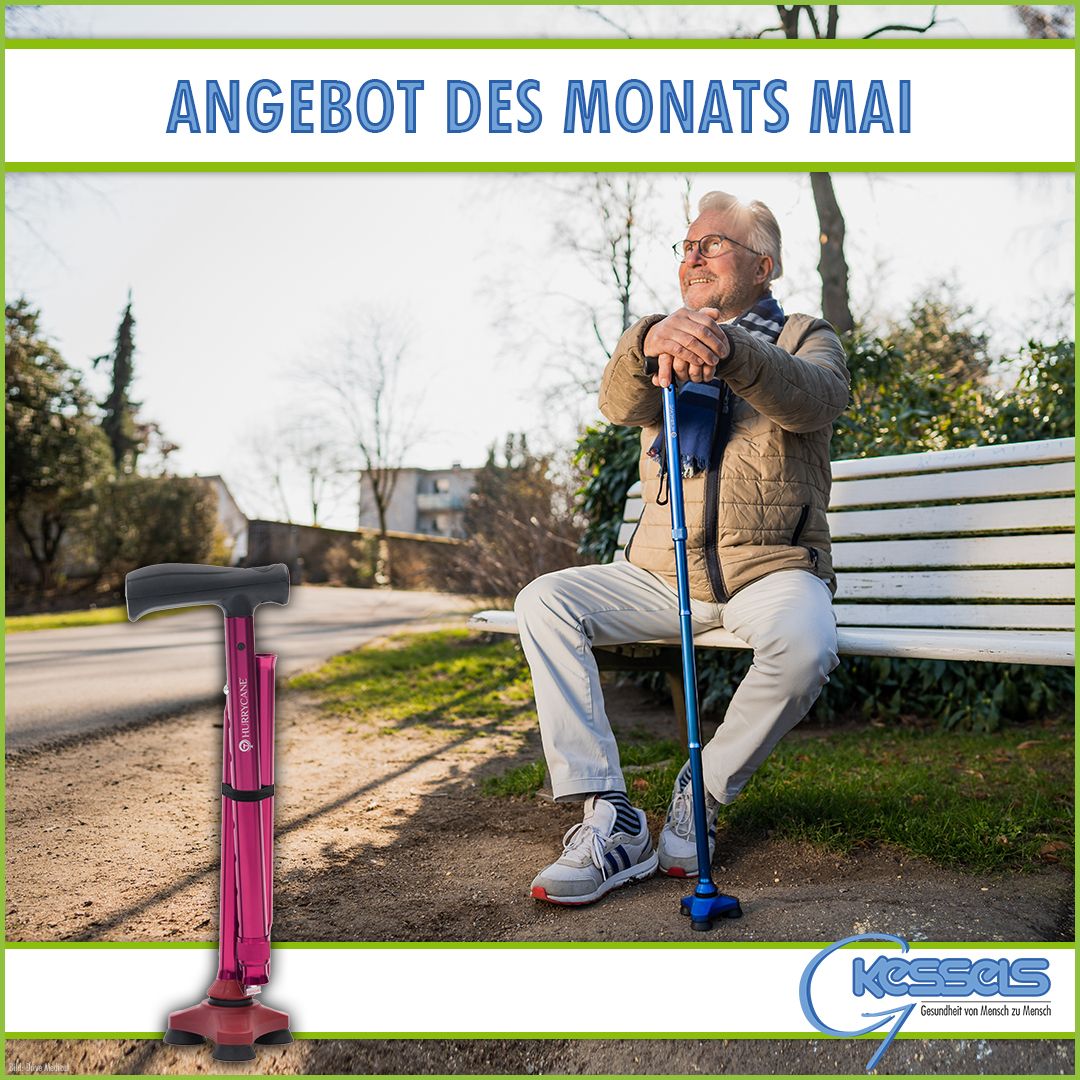 Eine Person sitzt an einem sonnigen Tag mit einem blauen Gehstock auf einer Parkbank, umgeben von Grün. Zu sehen ist eine rosa Gehhilfe.